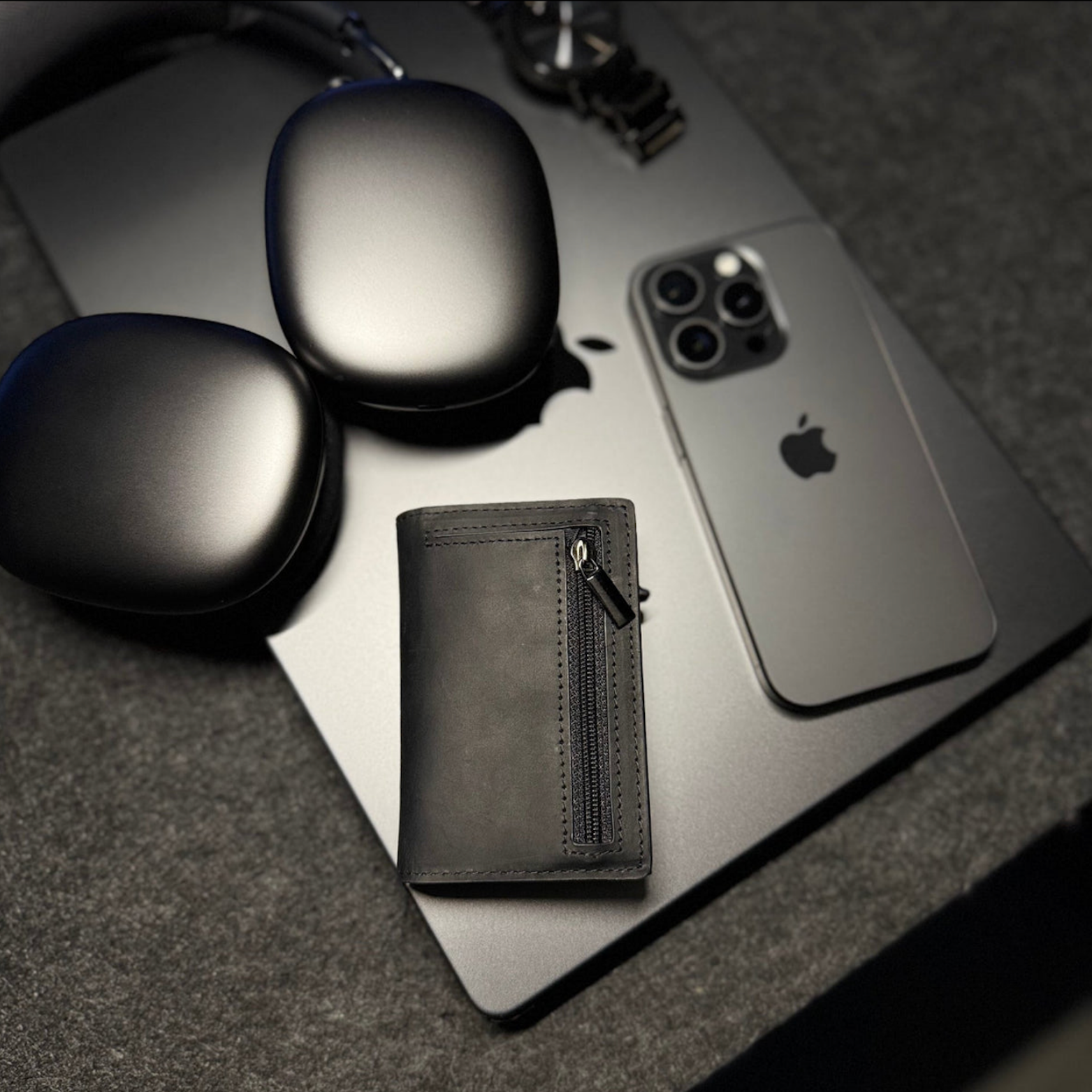 Wallet next to an iPhone, laptop and headphones